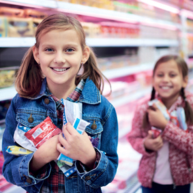 Two girls with sweets and chocolate bars at supermarket